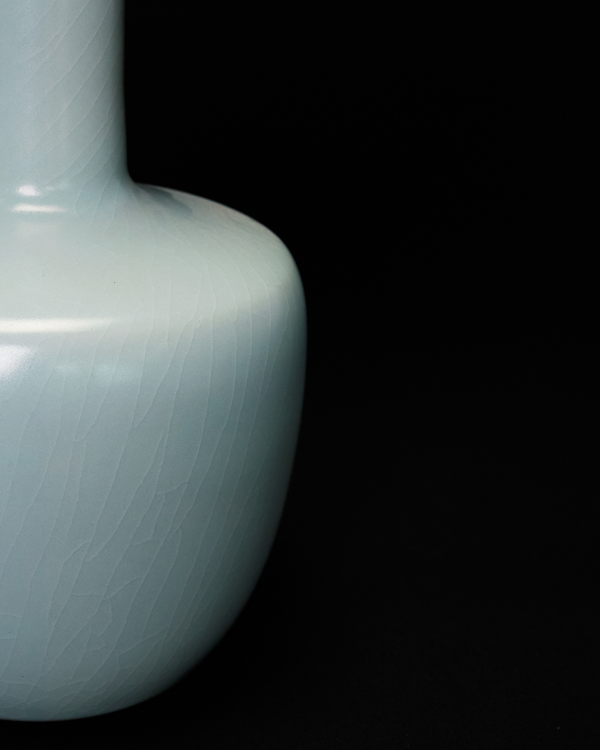 Close-up of the shoulder and body of the celadon vase with elongated crackle glaze lines.