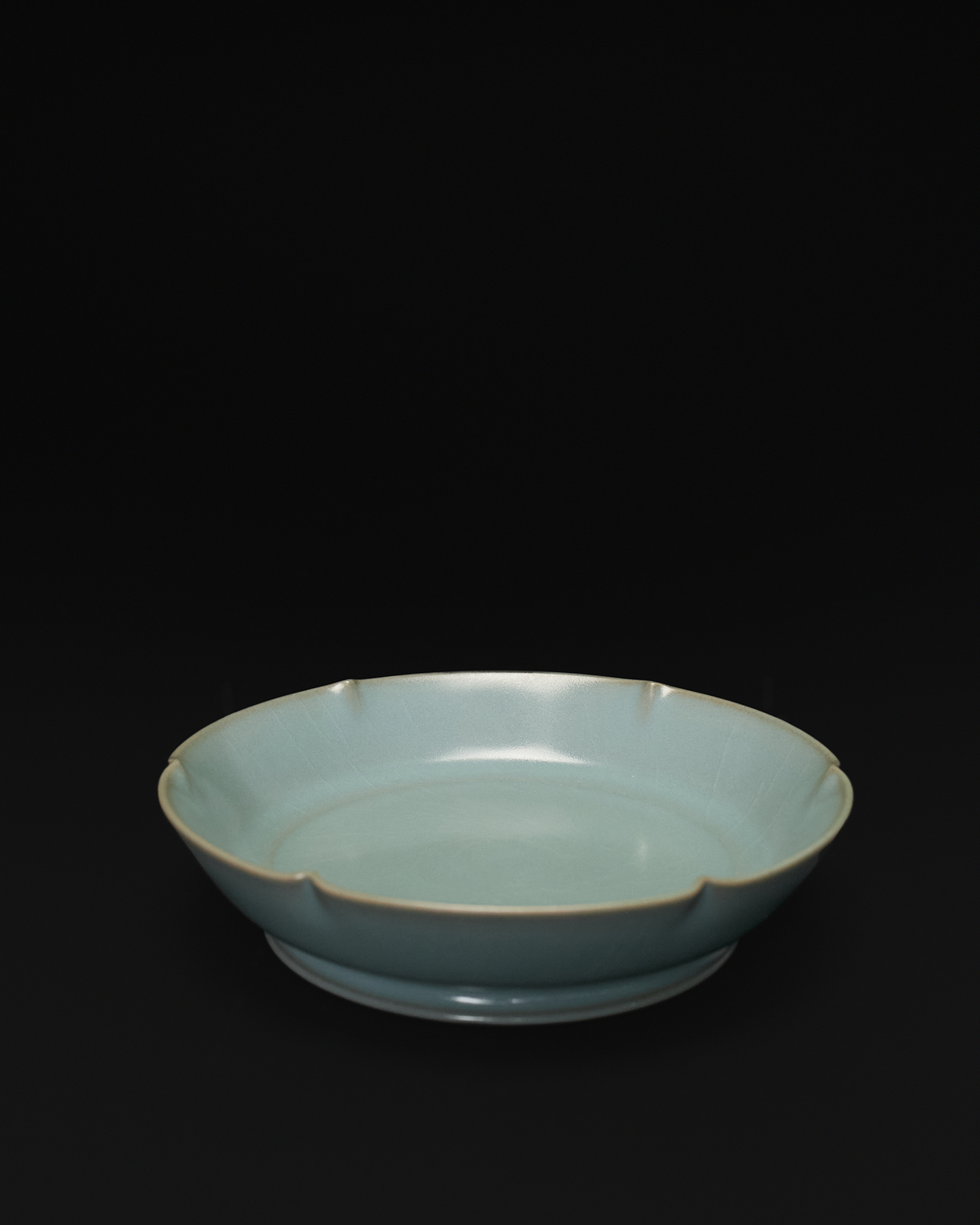 Angled front view of a celadon Chinese brush washer with a six-lobed mallow-shaped rim.