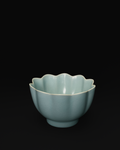 Three-quarter view of a Chinese celadon bowl with lotus-petal sides and a scalloped rim.