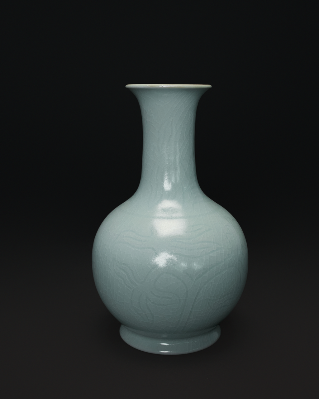 Front view of a Chinese celadon vase with a long neck, rounded body and carved floral pattern.