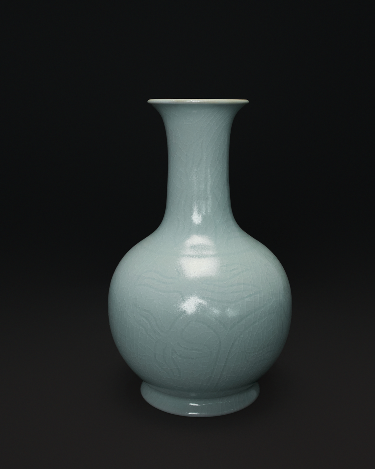 Front view of a Chinese celadon vase with a long neck, rounded body and carved floral pattern.
