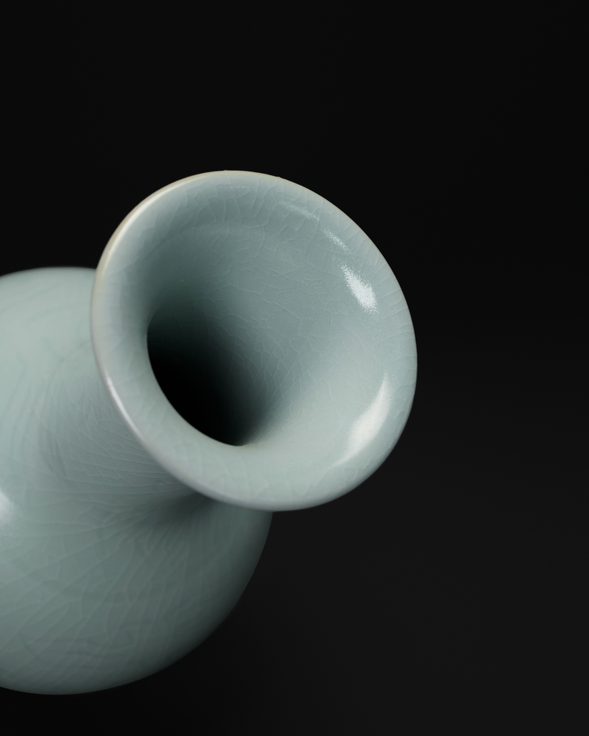 Close-up of the rounded flared rim and narrow opening of the Chinese celadon vase.