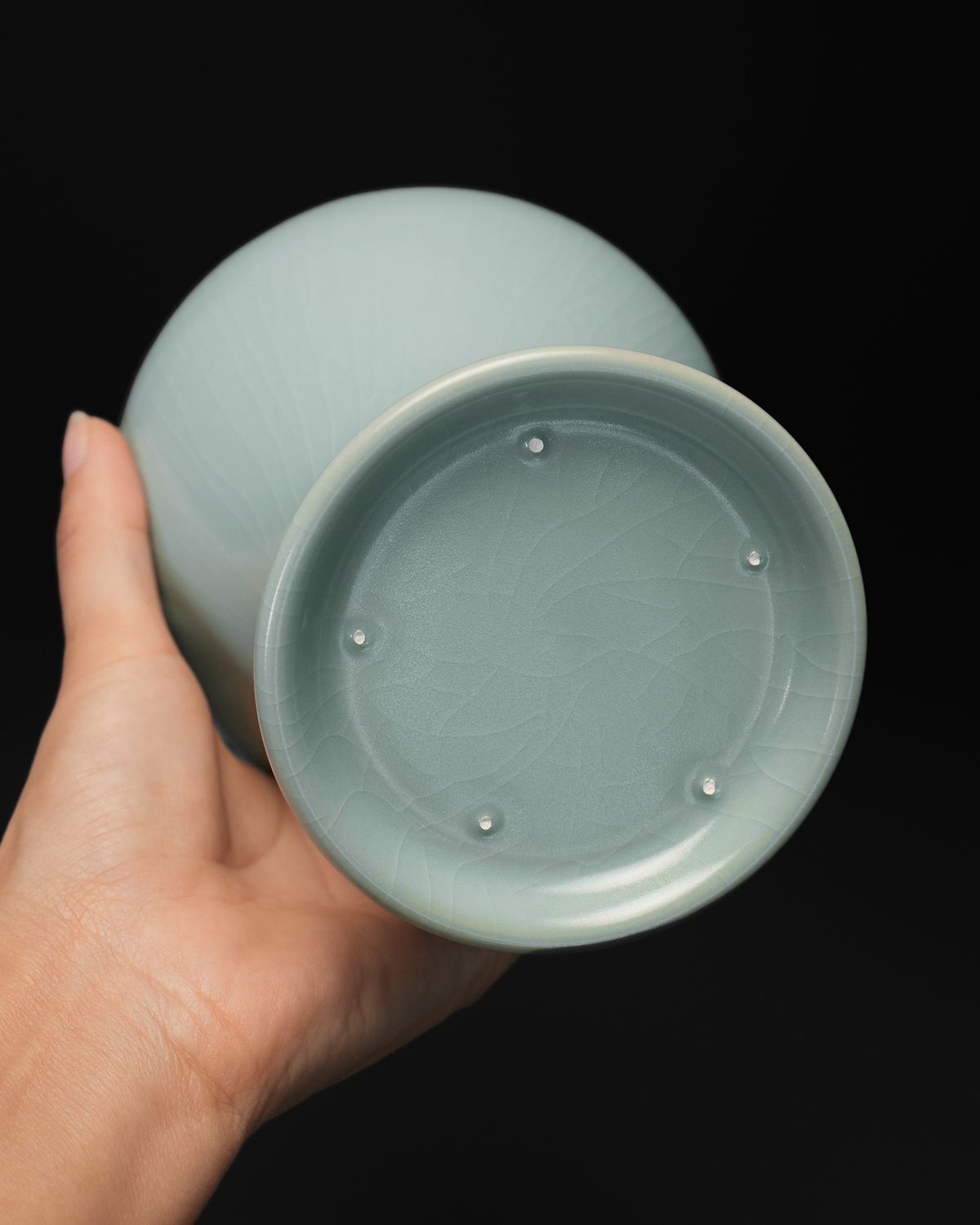 Handheld base view of the Guanyin vase showing the recessed foot and five visible spur marks.