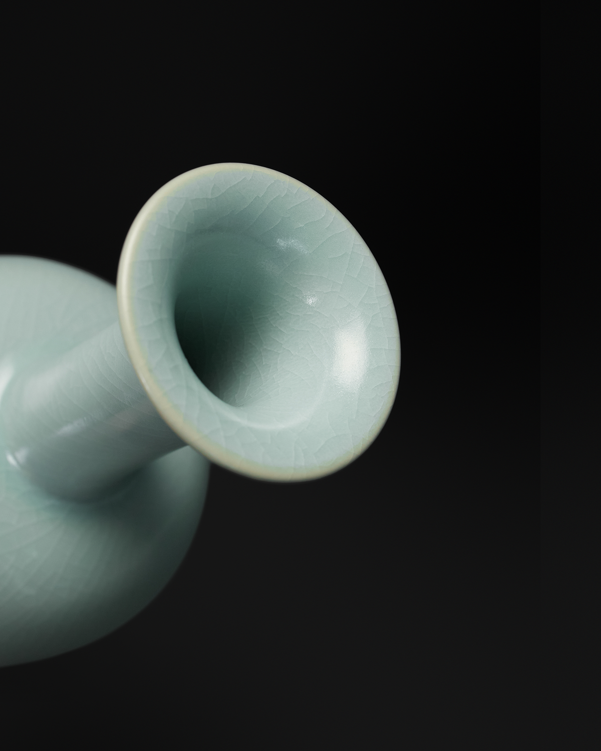 Angled close-up of the flared rim and crackle-glazed neck of the celadon long neck vase.