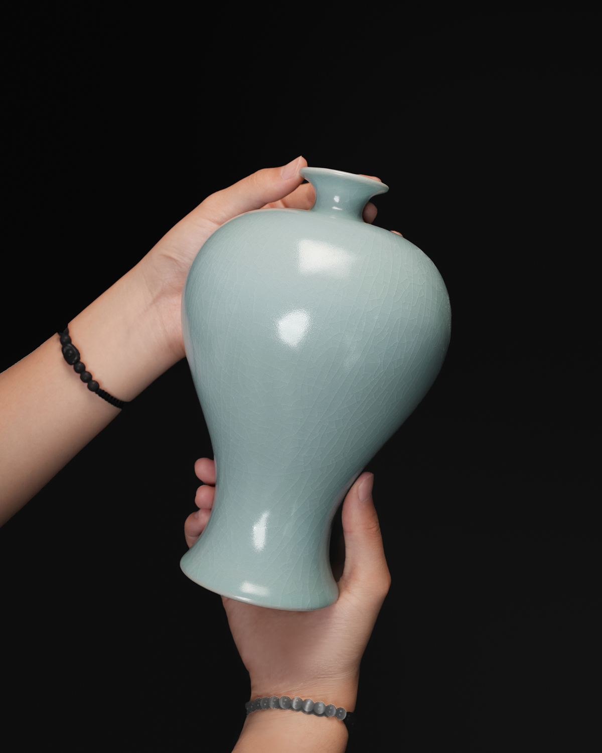 Handheld view of the celadon Meiping vase showing its scale, rounded shoulders and tapered form.