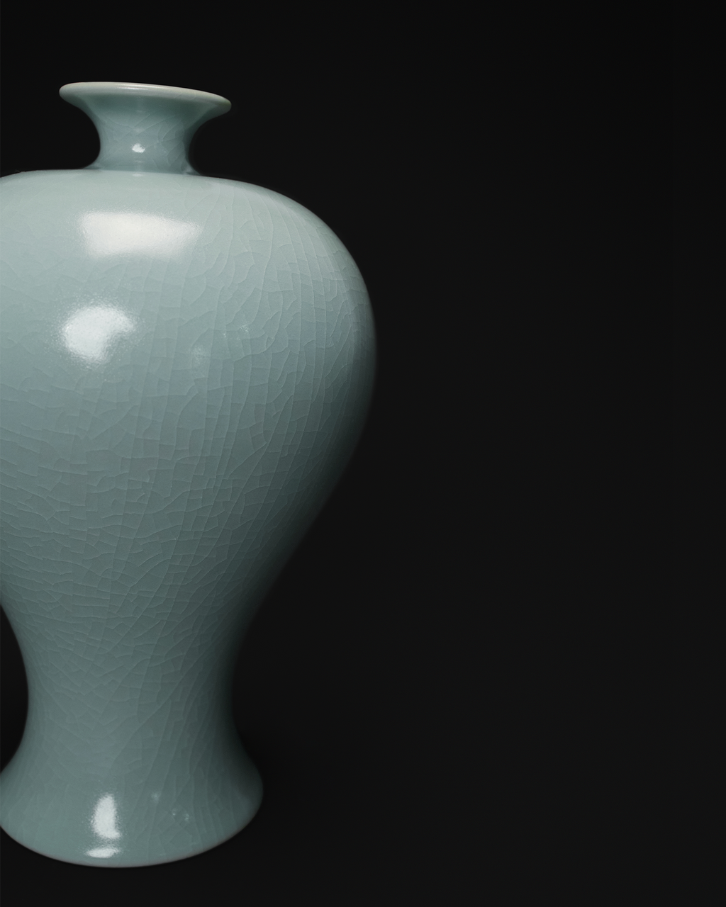 Close-up of the rounded shoulder, tapered profile and crackle glaze on a celadon Meiping vase.