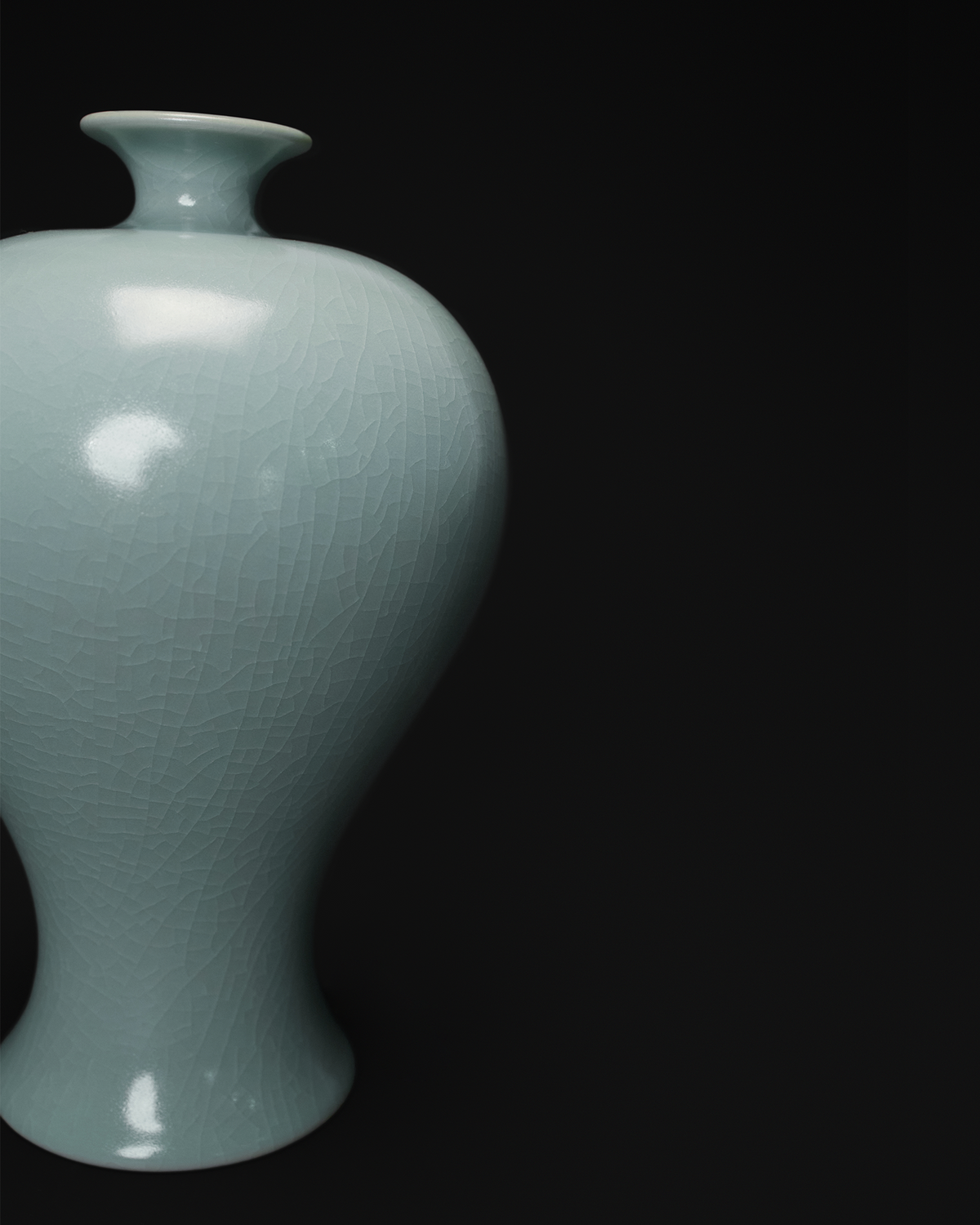 Close-up of the rounded shoulder, tapered profile and crackle glaze on a celadon Meiping vase.