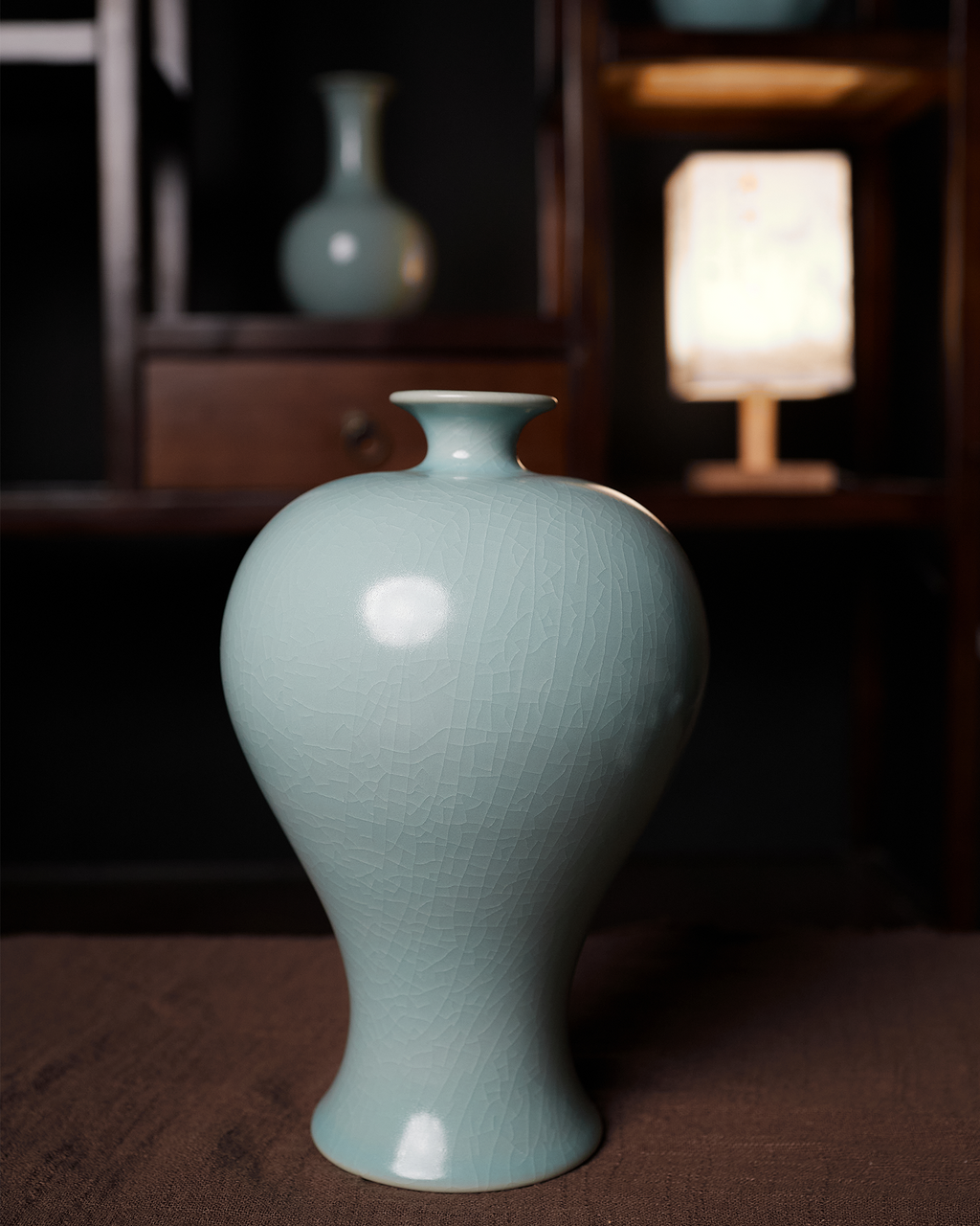 Celadon Meiping vase displayed in front of dark wooden shelving in a softly lit interior.