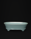Front view of a celadon narcissus basin with an oval body and raised feet on a black background.