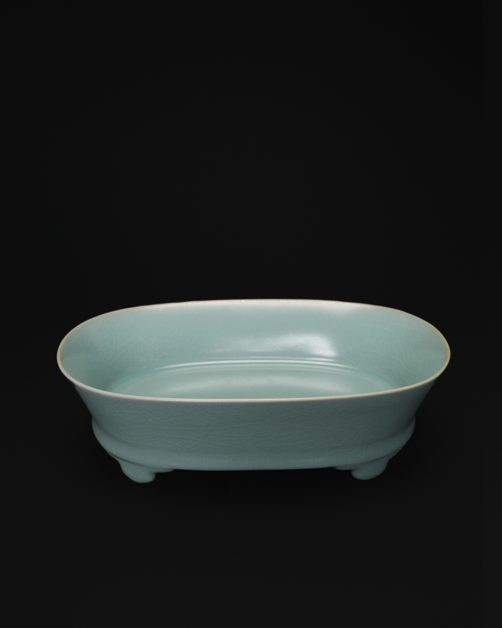 Three-quarter view of a celadon narcissus basin showing its oval interior and low raised feet.