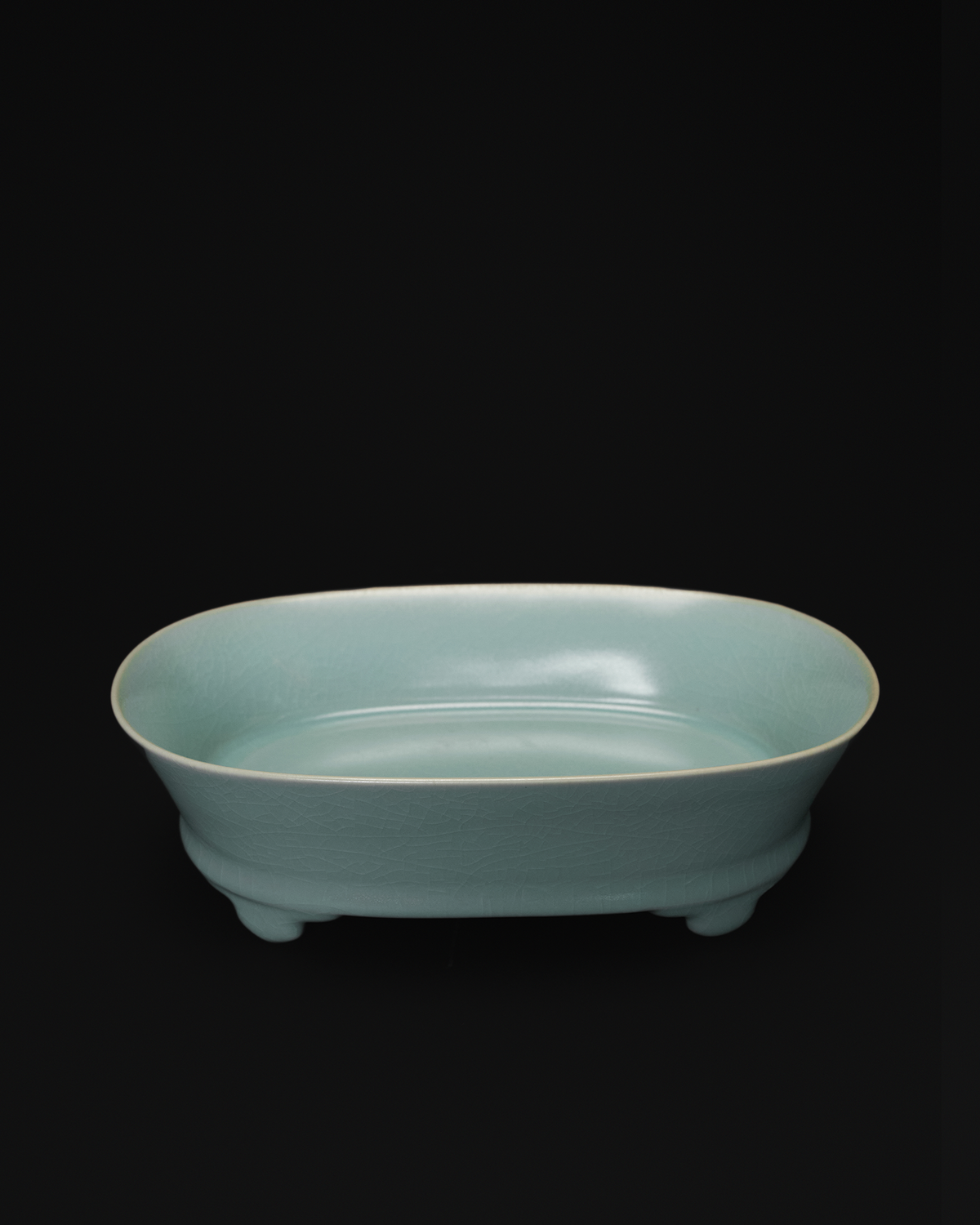 Three-quarter view of a celadon narcissus basin showing its oval interior and low raised feet.