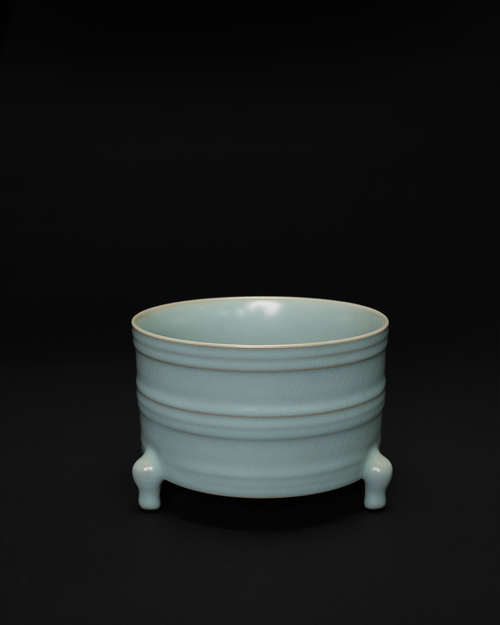 Front view of a ribbed ceramic vase with horizontal bowstring bands and three sculpted feet.