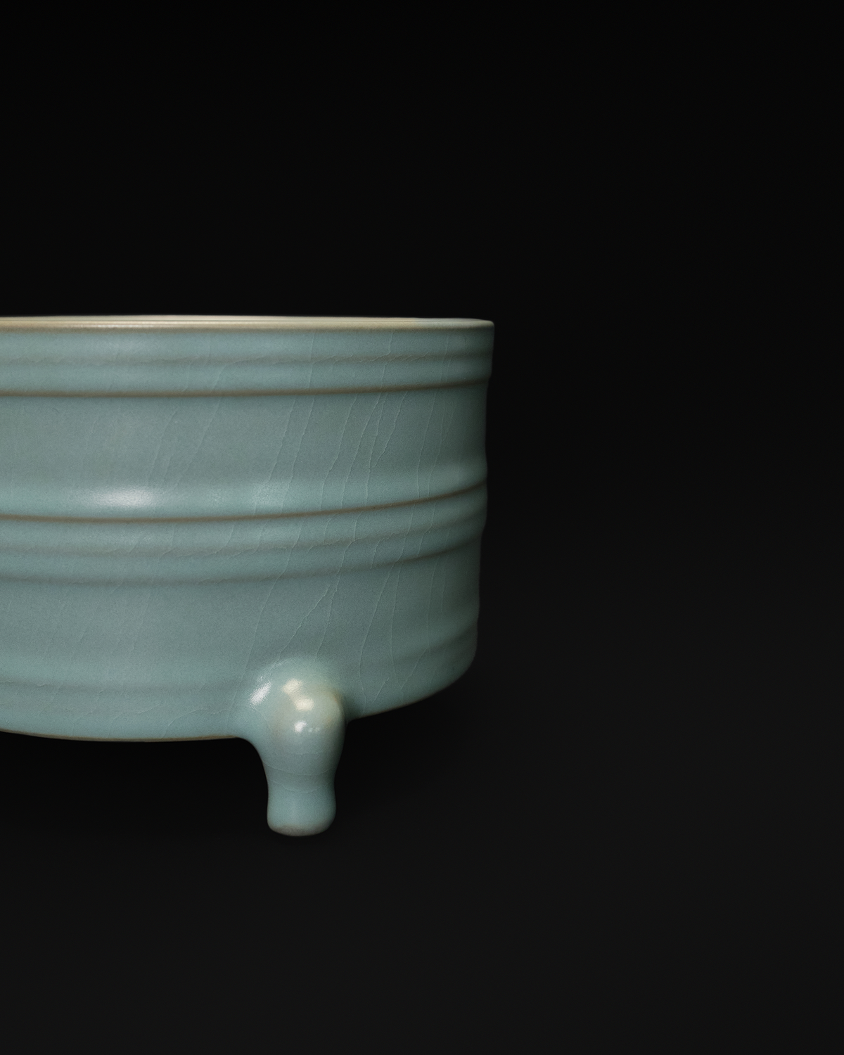 Close-up of the raised bowstring bands, crackle glaze and one foot on the ribbed ceramic vase.