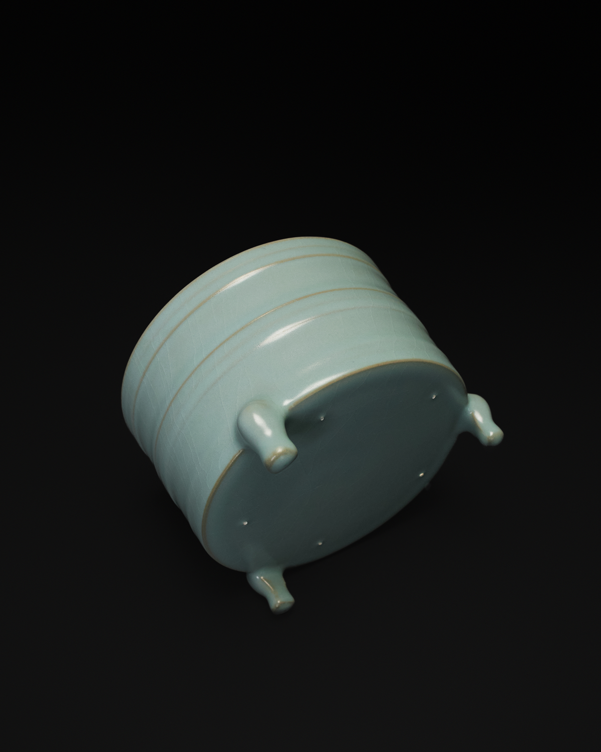 Angled underside view of the ribbed ceramic vase showing the three-footed construction.