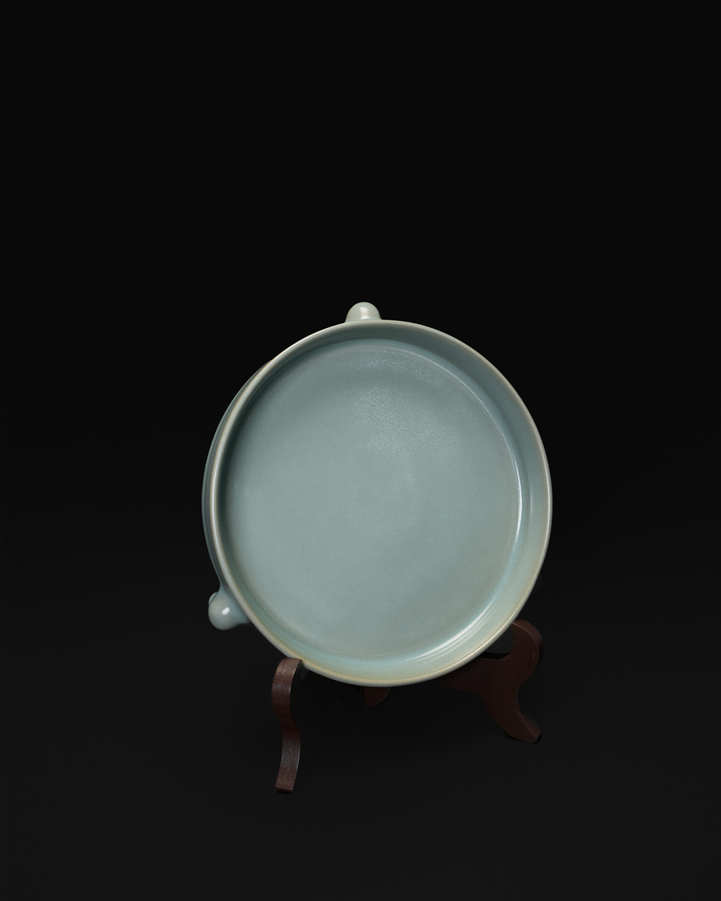 Top view of the celadon tripod bowl displayed upright on a wooden stand.